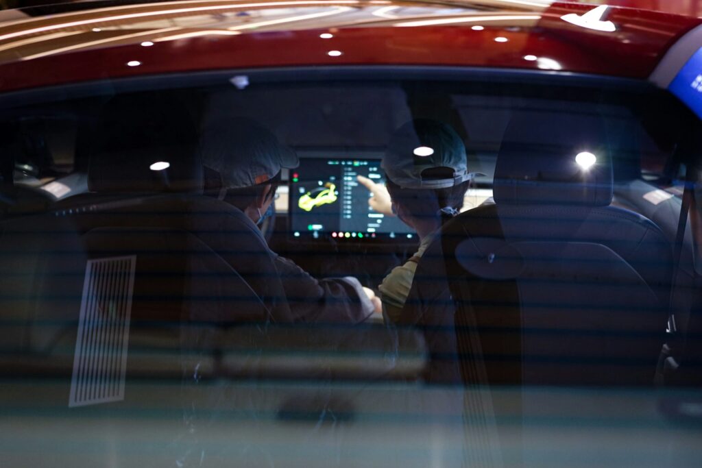 Two humans interacting with a human-machine interface (HMI) in an automobile.